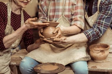 Cropped image of grandmother and grandfather with granddaughter making pottery at workshop clipart