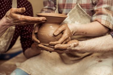 Cropped image of grandmother and grandfather with granddaughter making pottery at workshop clipart