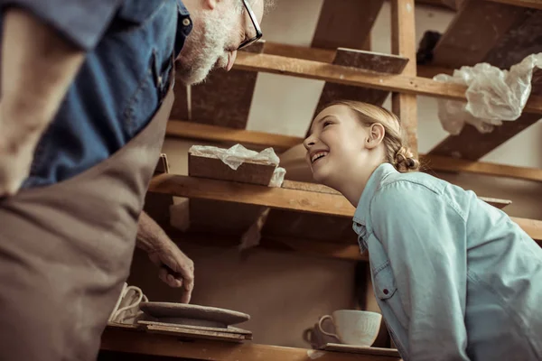 Abuelo explicando a la nieta cómo utilizar la rueda de cerámica — Foto de stock gratis