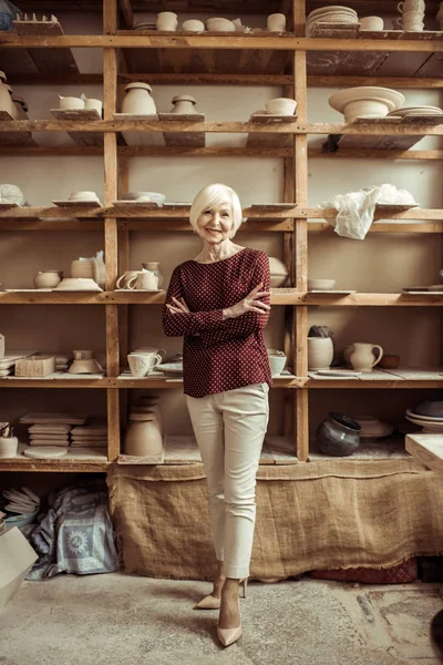 Front view of senior female potter standing at workshop — Stock Photo, Image