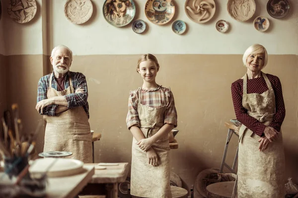 Grandmother and grandfather with granddaughter standing in a row at workshop — Stock Photo, Image
