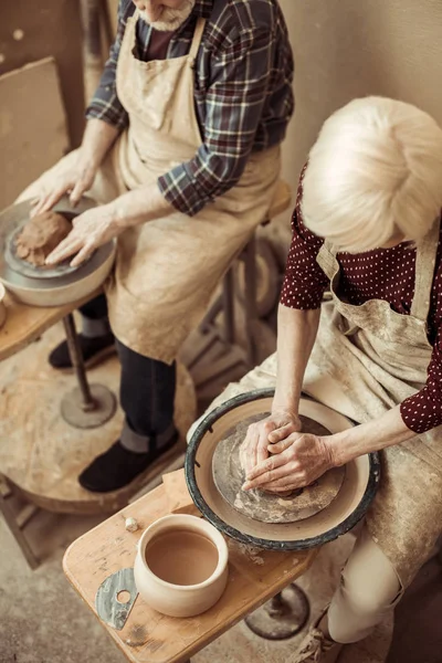 Overhead view of grandmother and grandfather making pottery at workshop — Free Stock Photo