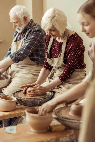 Großmutter und Großvater mit Enkelin beim Töpfern in der Werkstatt — Stockfoto