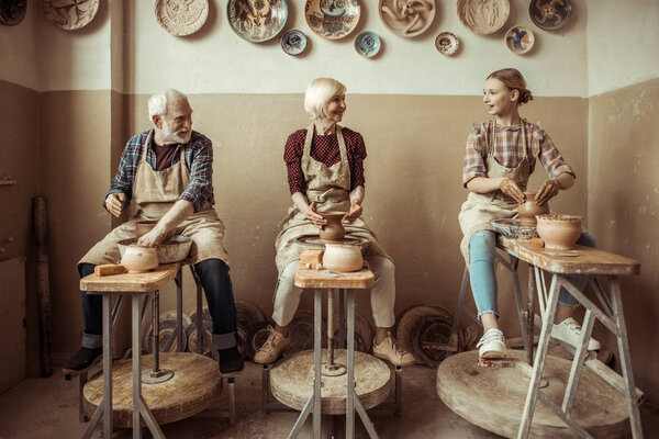 Grandmother and grandfather with granddaughter making pottery at workshop