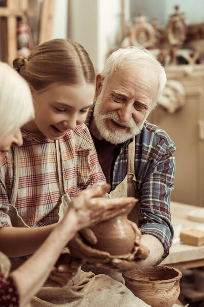 Grandmother and grandfather with granddaughter making pottery at workshop