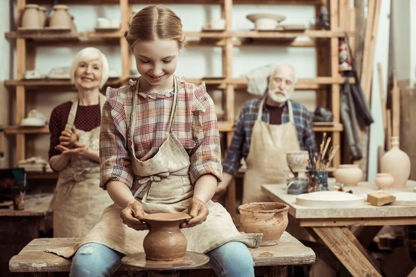 Бабушка и дедушка с внучкой делают керамику в мастерской — стоковое фото