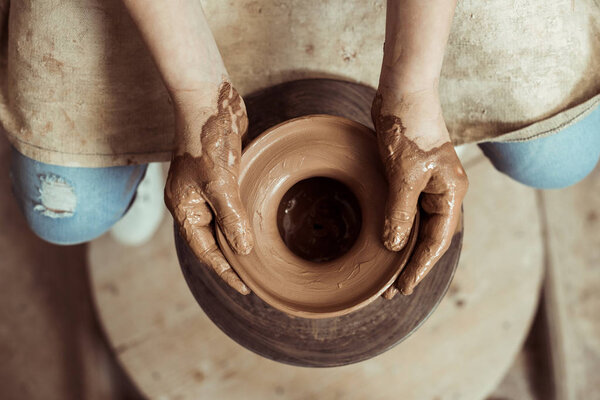Close up of child hands working on pottery wheel at workshop
