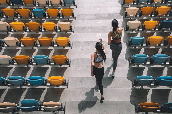 sportswomen running on stadium stairs