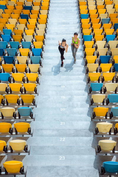 спортсменки бегают по ступенькам стадиона
