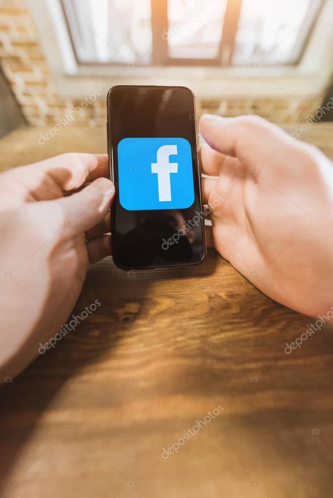 Man using smartphone with facebook logo icon on screen