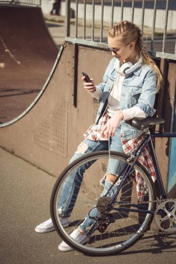 Girl with bike using smartphone  clipart