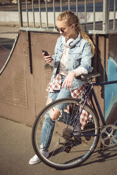 Chica con bicicleta usando teléfono inteligente — Foto de Stock