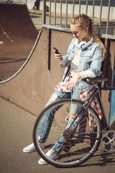 Girl with bike using smartphone — Stock Photo, Image