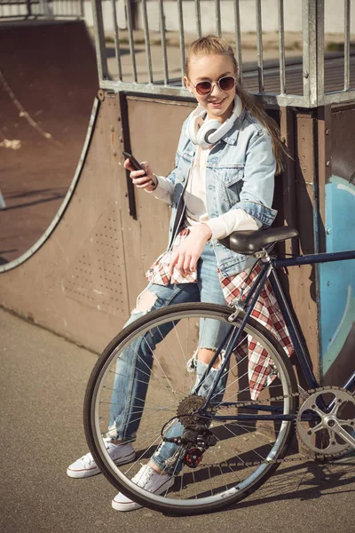 Girl with bike using smartphone — Free Stock Photo