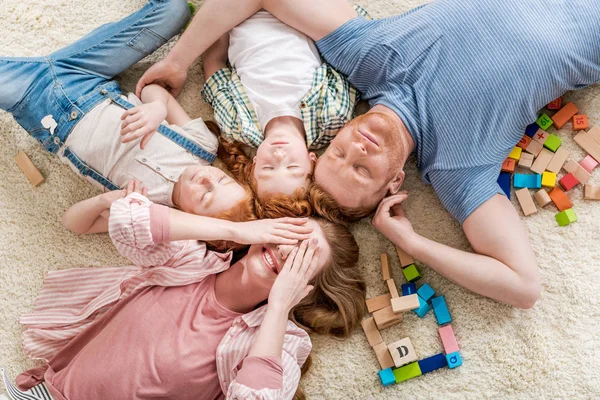 Família feliz deitada no chão — Fotografia de Stock