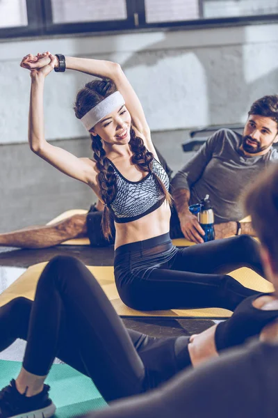 Athletic young people exercising in gym — Stock Photo, Image