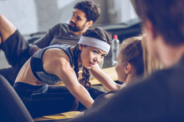 Athletic young people exercising in gym — Stock Photo, Image