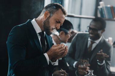 businessman smoking cigar with multicultural business team spending time behind