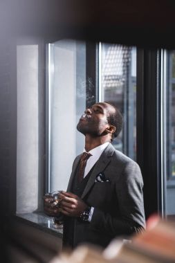 Sigara ve alkol cam elinde tutan emin iş adamı