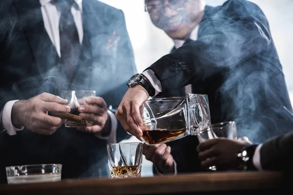 Cropped view of business team spending time, smoking cigars and drinking whiskey — Stock Photo, Image