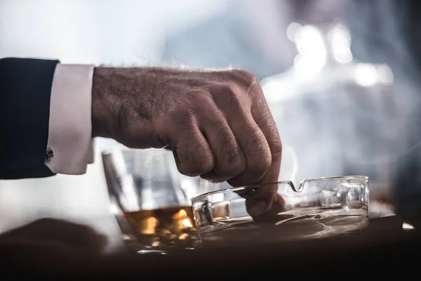 Beskuren bild av affärsmannen släckning cigarr i glas askkopp — Stockfoto