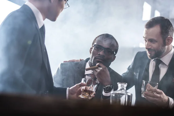 Multiethnische Gruppe von Geschäftsleuten, die gemeinsam Whiskey trinken und rauchen, multikulturelles Business-Team — Stockfoto