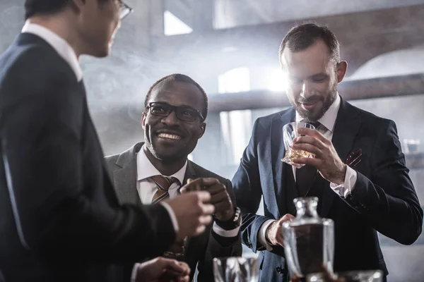 Multiethnic group of businessmen spending time together drinking whiskey and smoking, multicultural business team — Stock Photo, Image