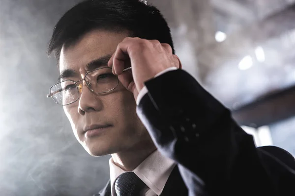 Портрет уверенного азиатского бизнесмена в очках, смотрящего в сторону — стоковое фото