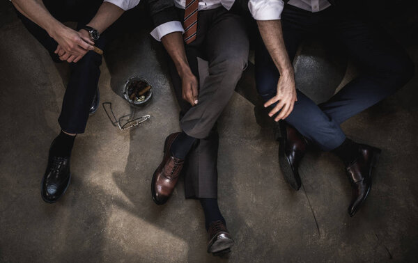 Обрезанный снимок группы бизнесменов, сидящих на полу вместе
