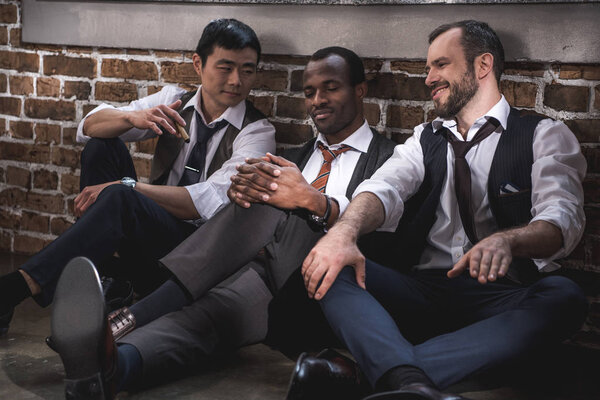 group of smiling stylish businessmen resting together after work