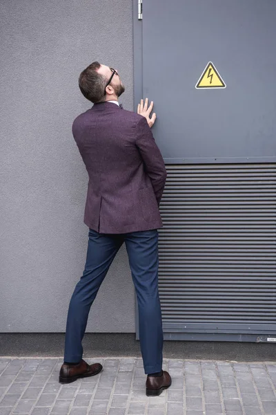 Back view of stylish businessman peeing on street near transformer — Stock Photo, Image