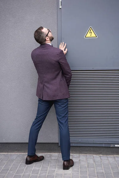 Vista trasera de un hombre de negocios elegante orinando en la calle cerca del transformador — Foto de Stock