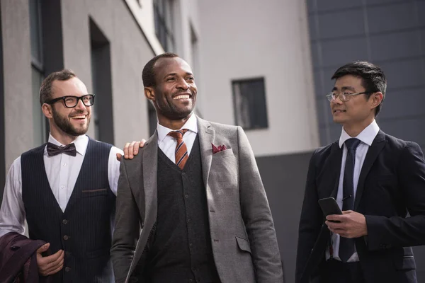 Молодые стильные мультиэтнические бизнесмены в формальной одежде прогулки на свежем воздухе, деловая встреча команды — стоковое фото