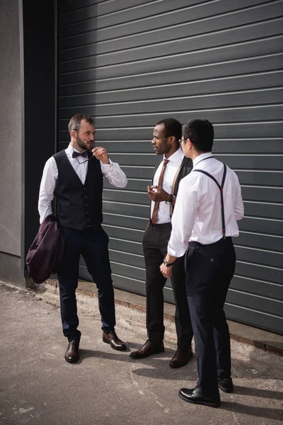 Young multiethnic businessmen in formalwear talking at break outdoors, business team meeting — Stock Photo, Image