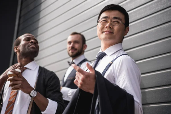 Молодые стильные многонациональные бизнесмены в формальной одежде, стоящие на открытом воздухе, деловая встреча — стоковое фото