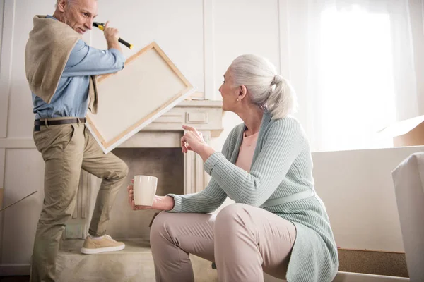 Man hanging picture on wall — Stock Photo, Image