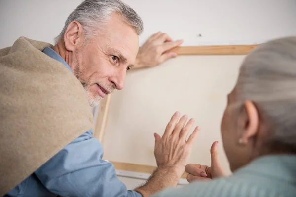 Pareja de ancianos colgando foto en la pared — Foto de Stock