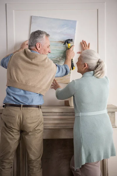 Pareja de ancianos colgando foto en la pared — Foto de Stock