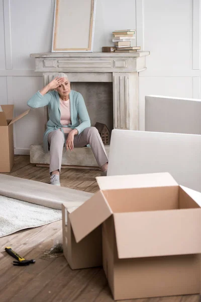 Tired woman sitting on fireplace — Stock Photo, Image