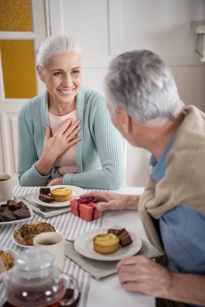 Senior man presenting gift to wife — Stock Photo, Image