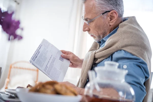 Man reading newspaper during breakfast — Stock Photo, Image