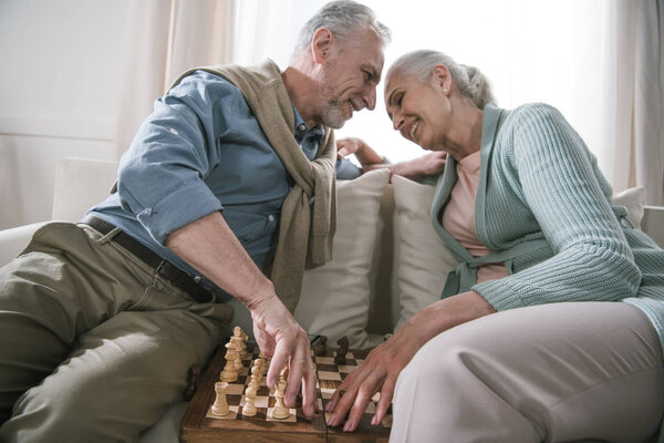 пожилая пара обнимается во время игры в шахматы
