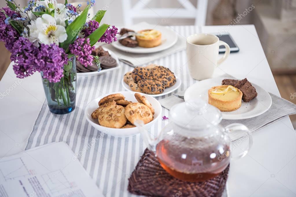 lilac flowers with tea and various pastry
