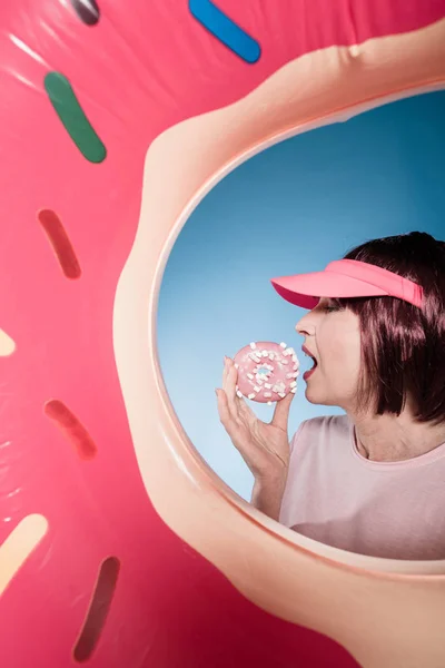 Woman eating doughnut into swimming tube — Stock Photo, Image