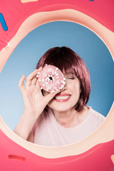 Woman holding doughnut in front of eye — Stock Photo, Image