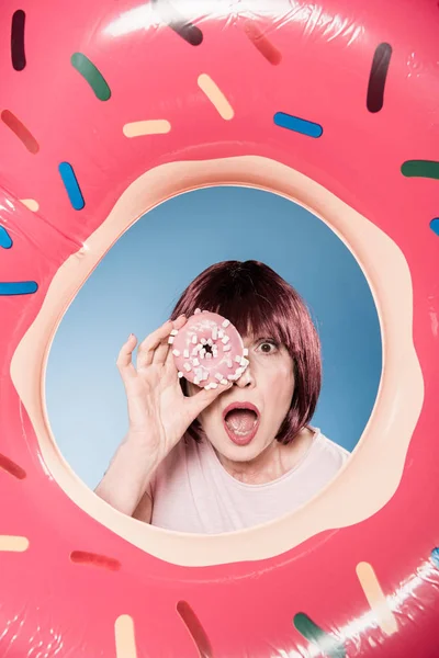Женщина держит пончик перед глазами — Бесплатное стоковое фото