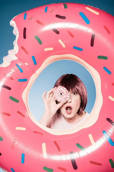 Woman holding doughnut in front of eye — Free Stock Photo