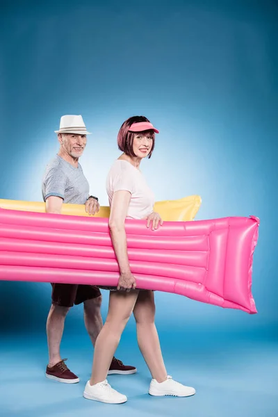 Senior couple holding swimming mattresses — Stock Photo, Image