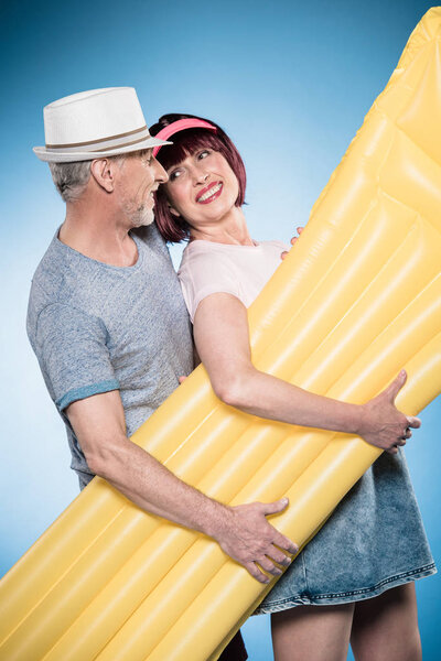 пожилая пара держит плавательный матрас
