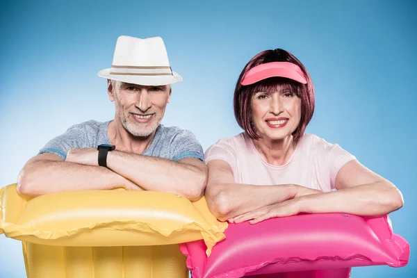 Senior couple leaning on swimming mattresses — Stock Photo, Image